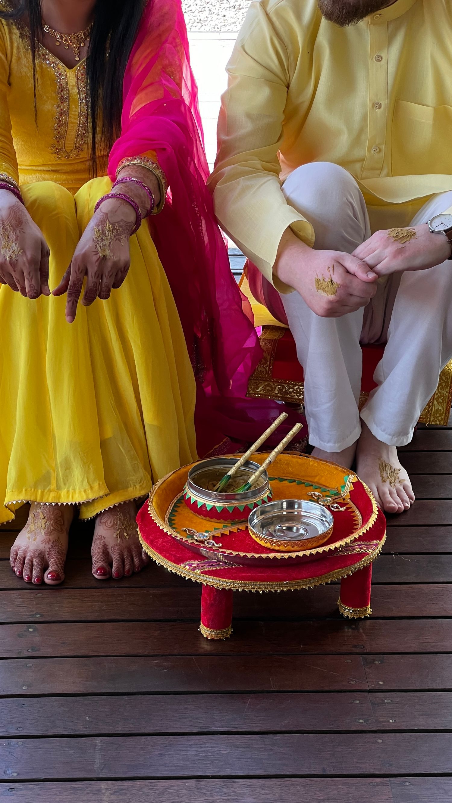 Traditional Indian mehndi setup with red low table and metal bowls for henna application. indian wedding new zealand