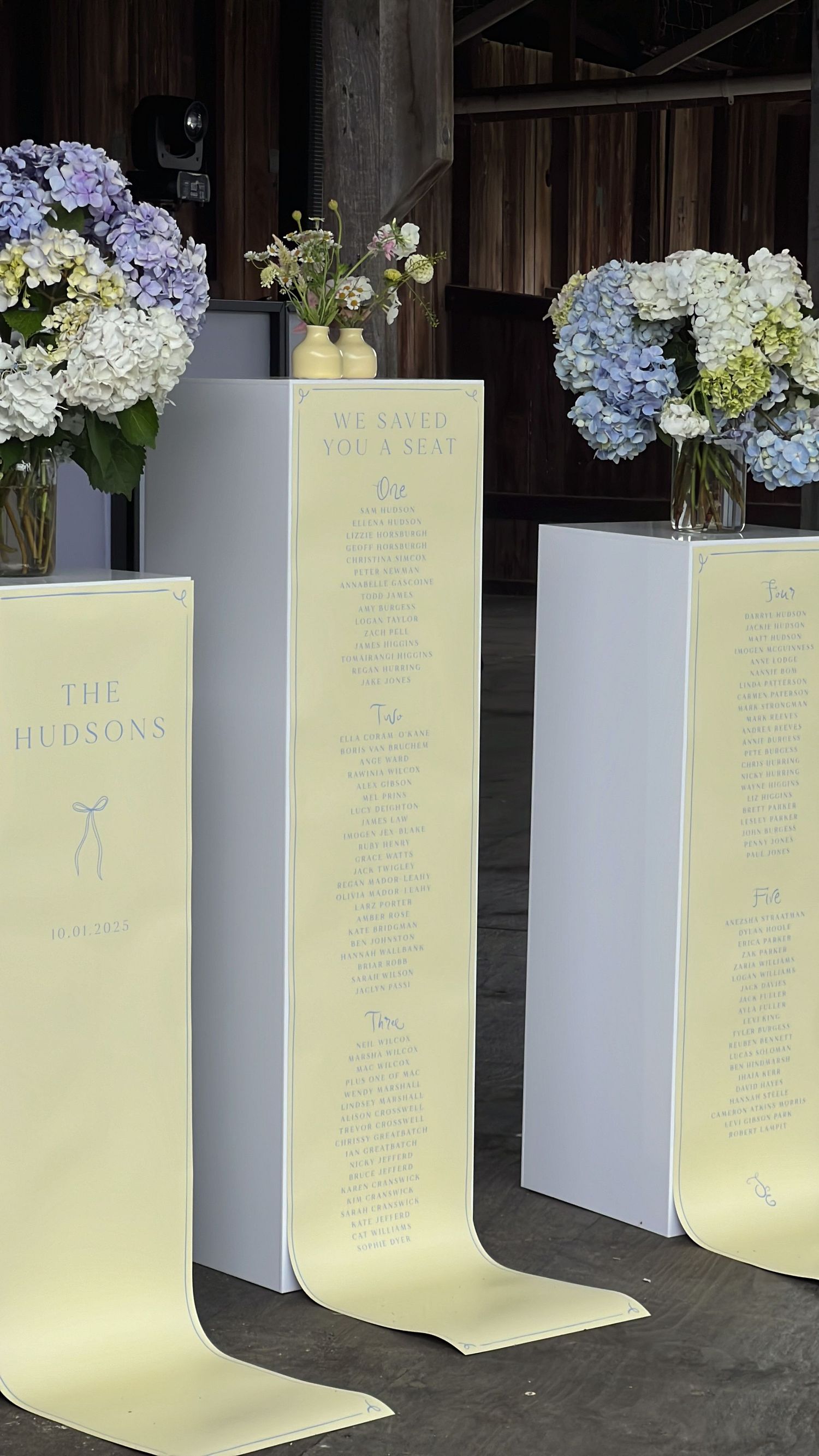 Illuminated seating chart displays with hydrangea flower arrangements for wedding reception.