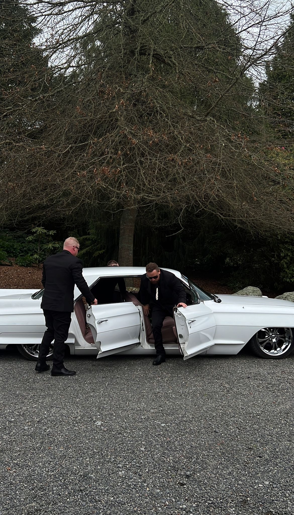 A series of four images showing people examining damage to a long white limousine parked on gravel under trees.
