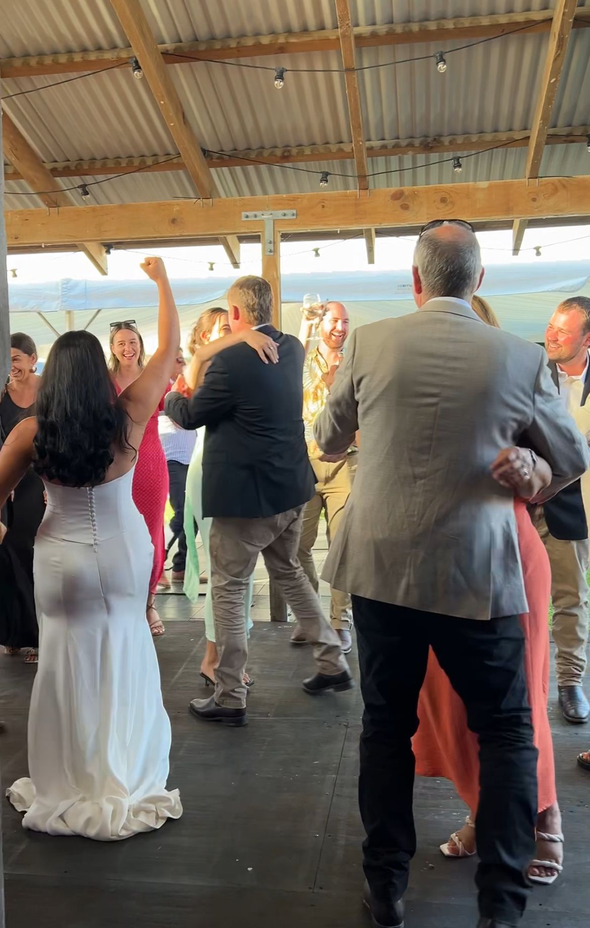 People dancing together on a covered outdoor dance floor at what appears to be a social gathering or celebration.