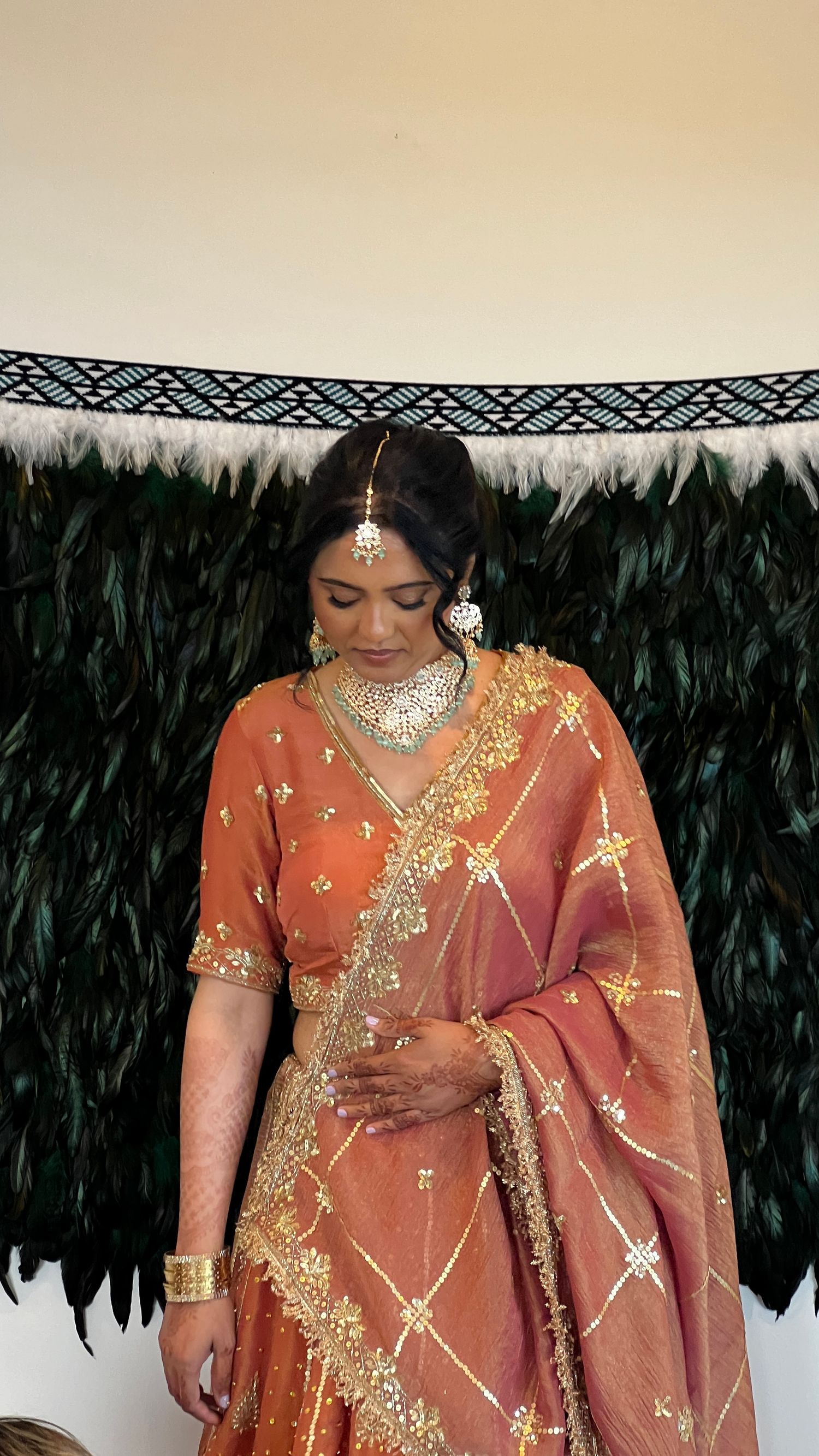 Traditional Indian bridal attire in peach with gold embellishments and jewelry.