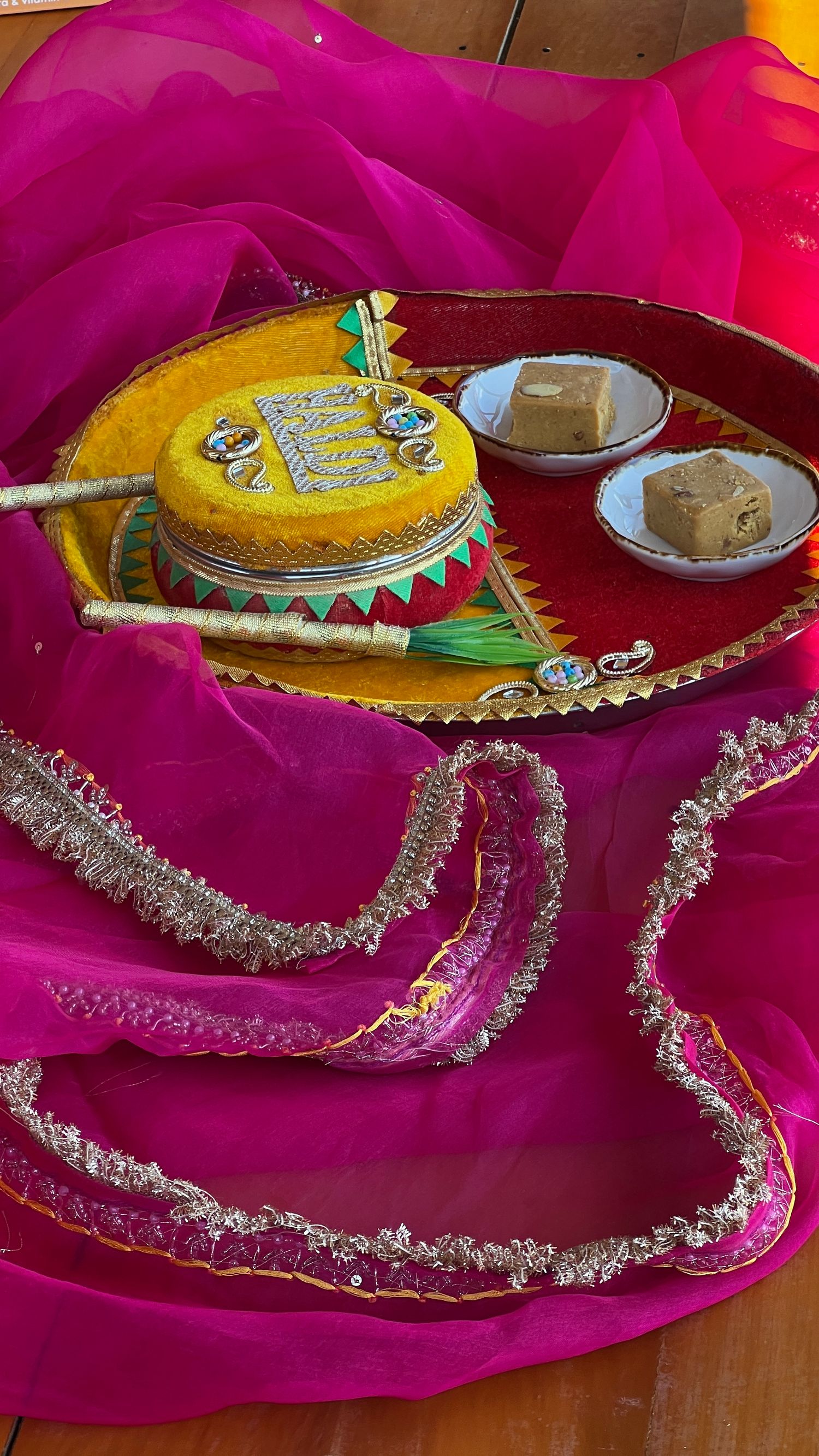 Decorative yellow sombrero and pink fabric with silver trim displayed on a wooden surface for a festive celebration.