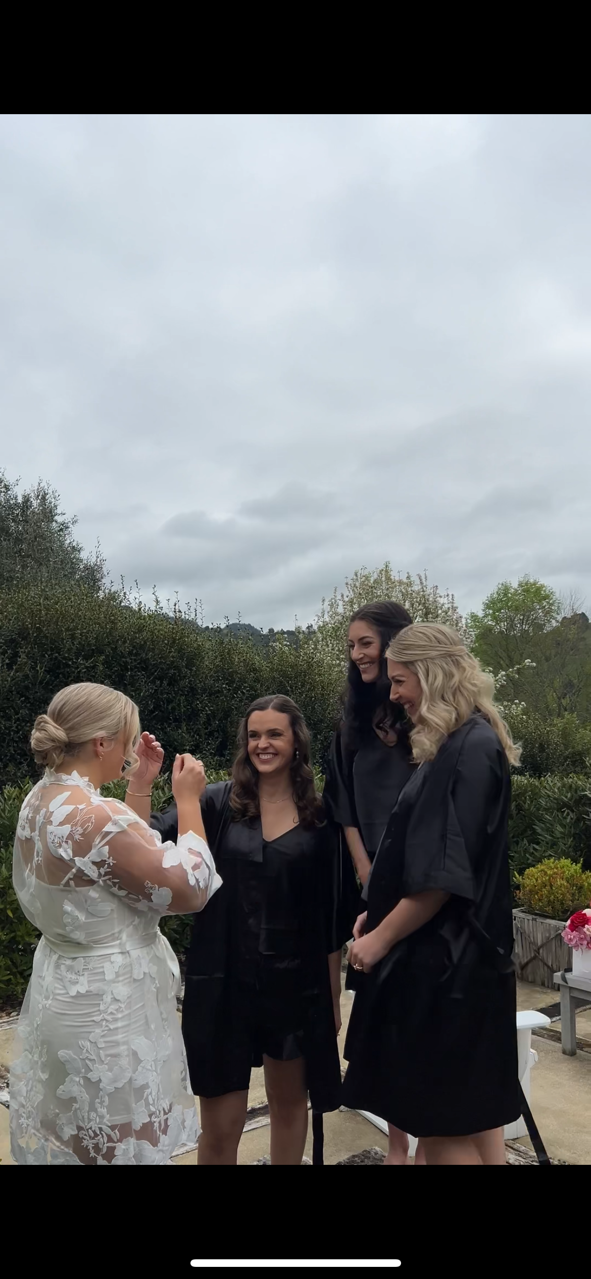Wedding party in black and white attire sharing joyful moment outdoors.