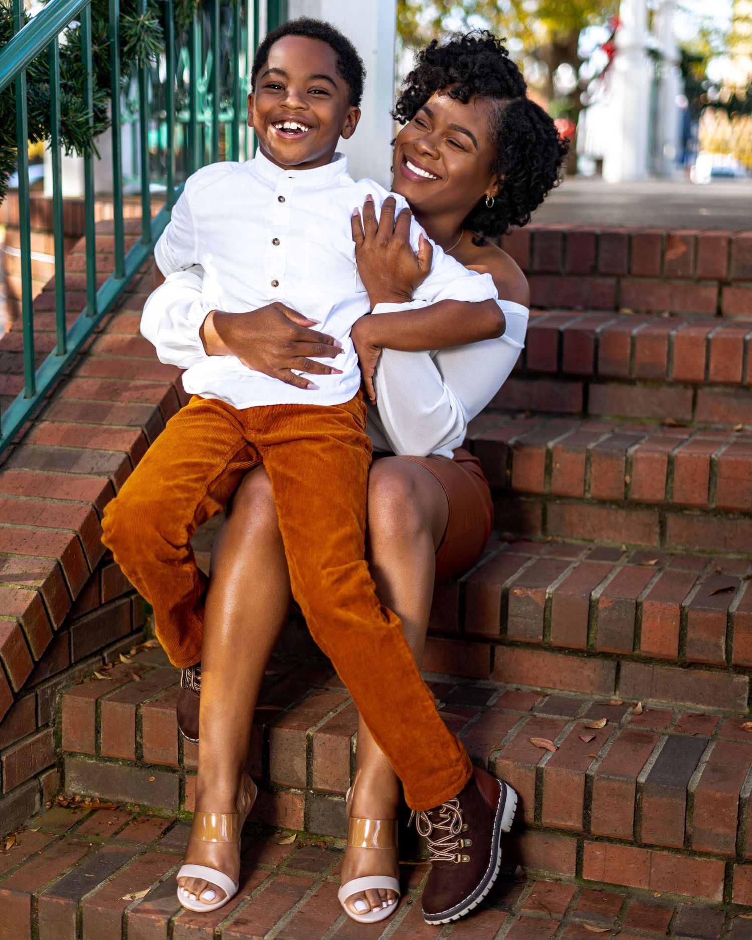 Mother and son portrait in Roswell, Georgia — joyful pair seated on brick steps in coordinating white and rust tones. Captured by Murray Vis