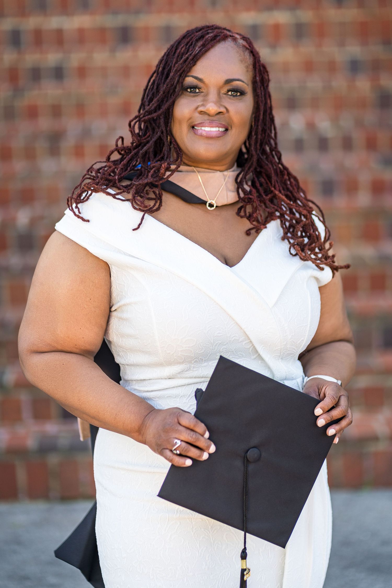 Classic graduation portrait of a Black woman with locs, captured at the Clark University — timeless lighting and elegant academic