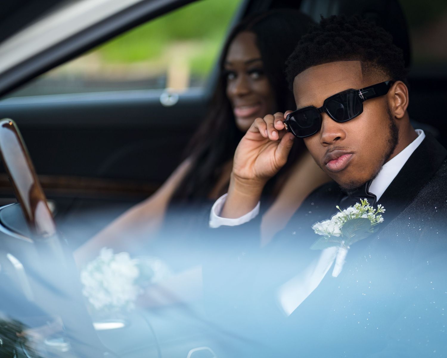 Prom portrait in Atlanta, Georgia — young black couple dressed in formal attire posing in a luxury car before their event.