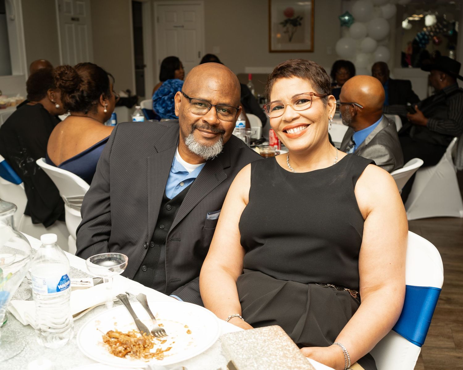Black Couple smiling at a formal dinner in Austell, Georgia — an elegant moment captured during a community celebration.