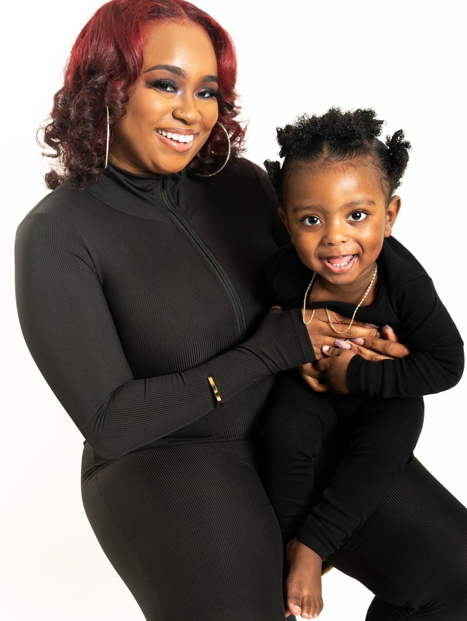 Family portrait in Powder Springs, Georgia — joyful mother and child wearing matching black outfits against a bright studio backdrop.