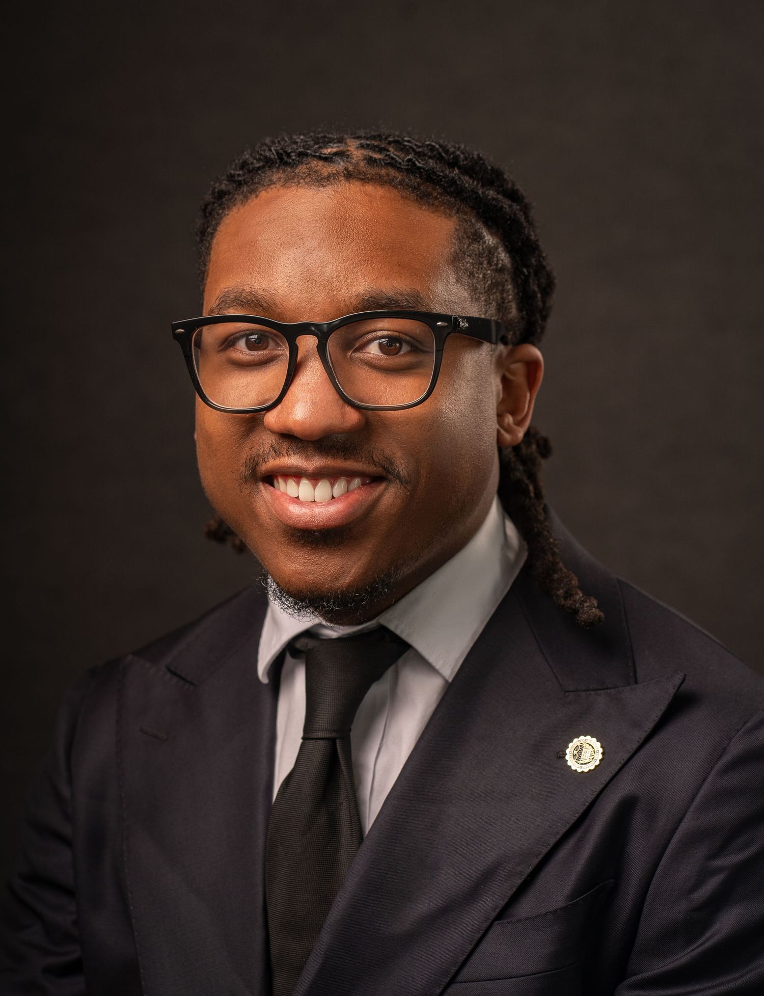 Professional headshot in Marietta, Georgia — confident black man in suit and tie posing against a dark studio backdrop.