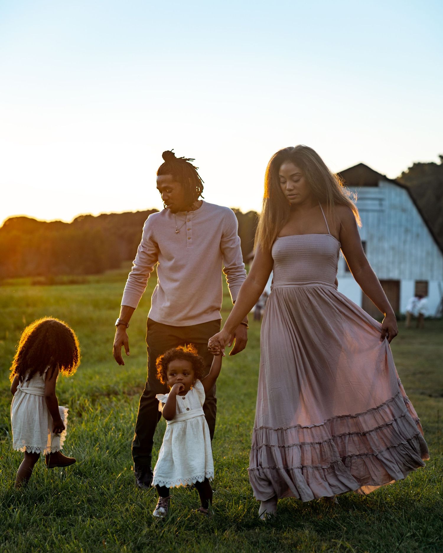 Lifestyle family photo session in Acworth, Georgia — parents and children walking hand-in-hand at sunset in a scenic open field.