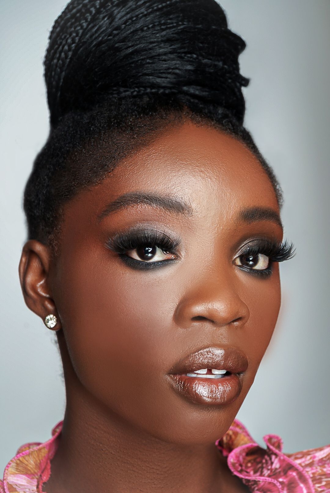 High-end beauty portrait in Atlanta, Georgia — black elegant woman with flawless makeup and braided updo captured under studio lighting.