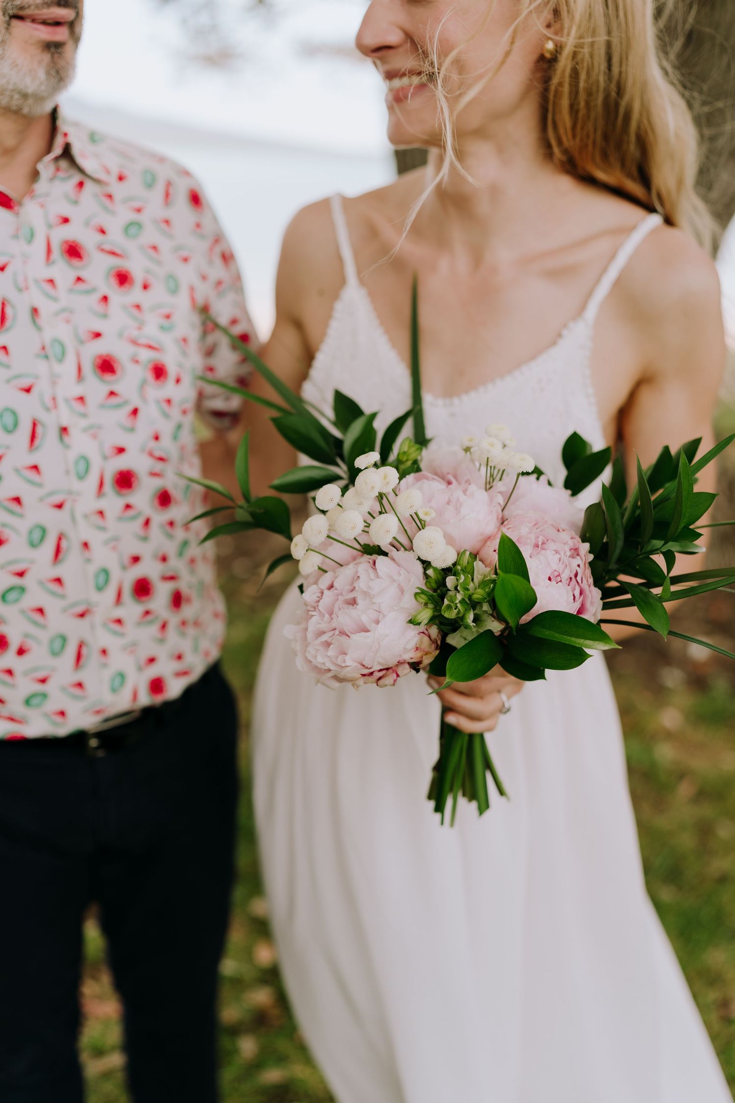 Close-up detail shots of pink floral bouquets and white dresses at an outdoor wedding celebration.