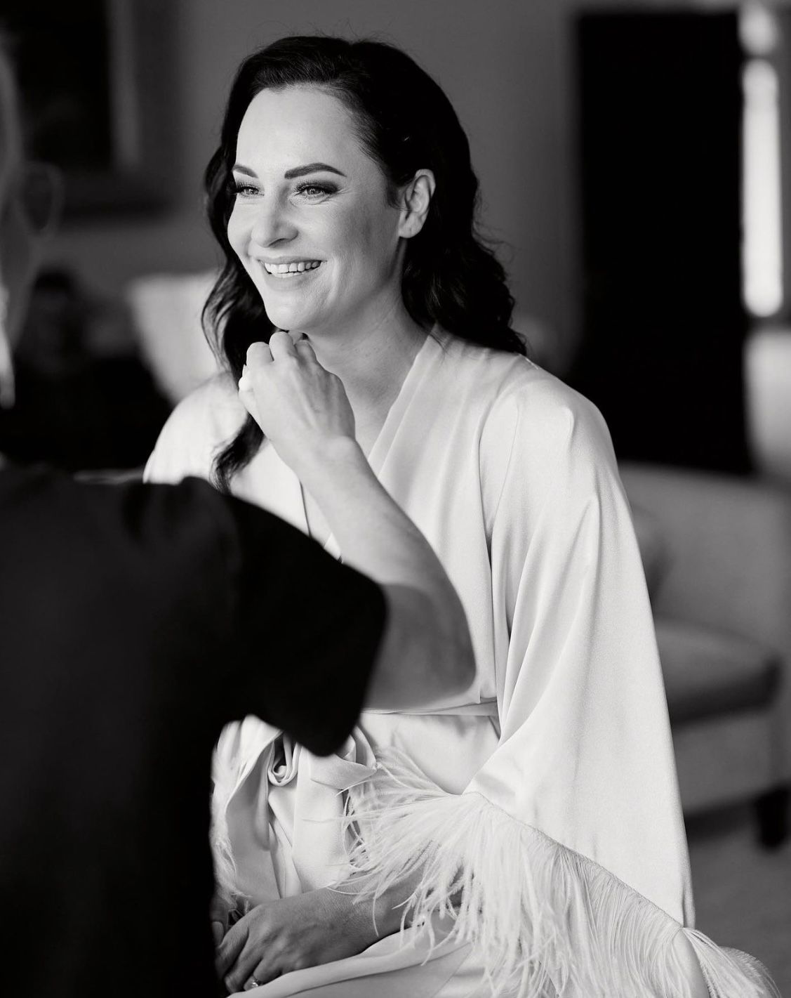 Black and white boudoir photography series showing woman in white robe with feather details.