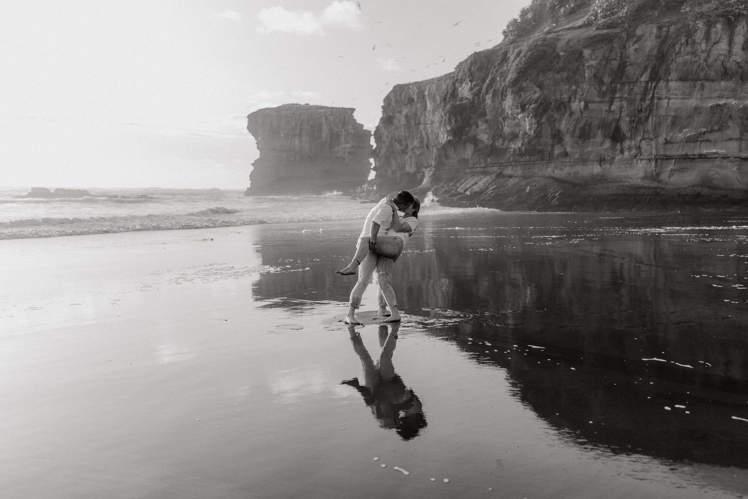 Dramatic black and white panorama of coastal cliffs and ocean waves.