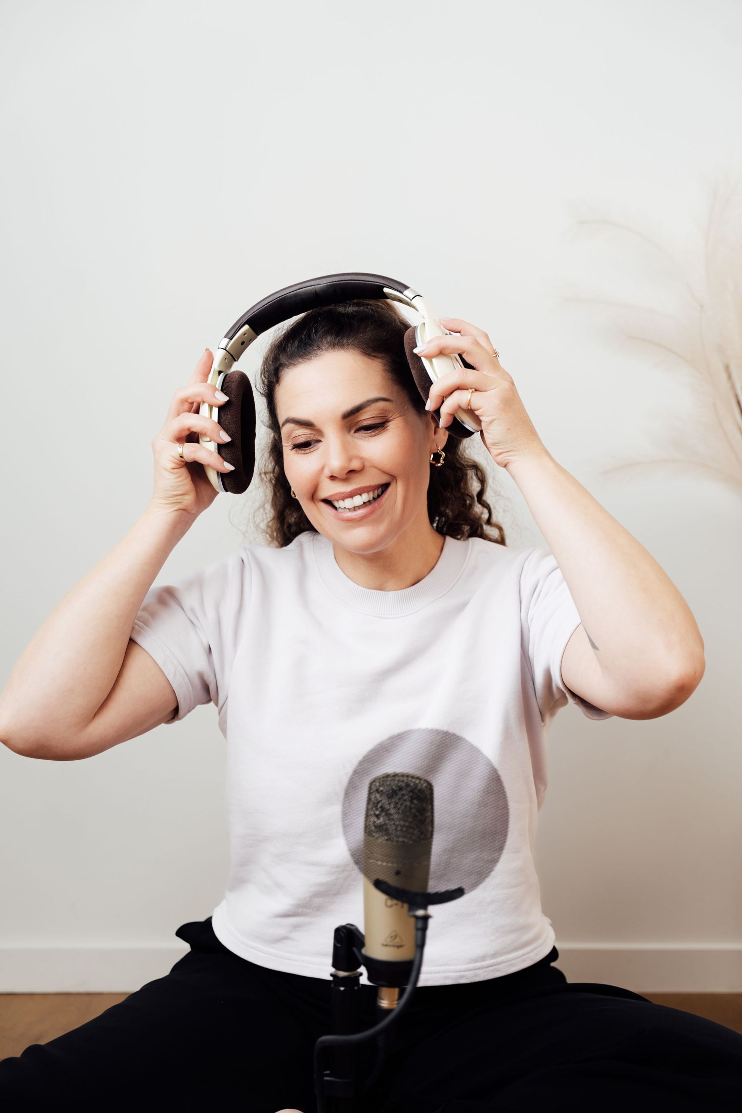Happy woman putting on headphones in front of a studio microphone.