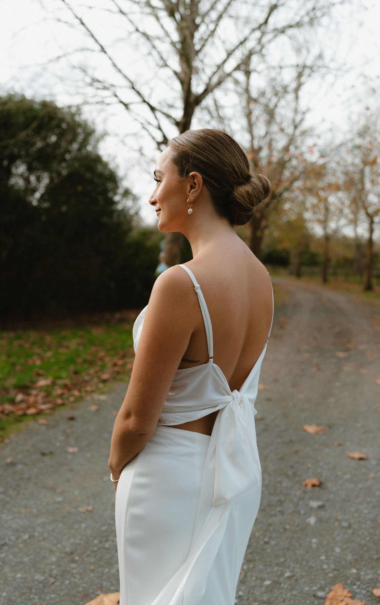 Wedding dress detail showing bow-tied open back on autumn path.