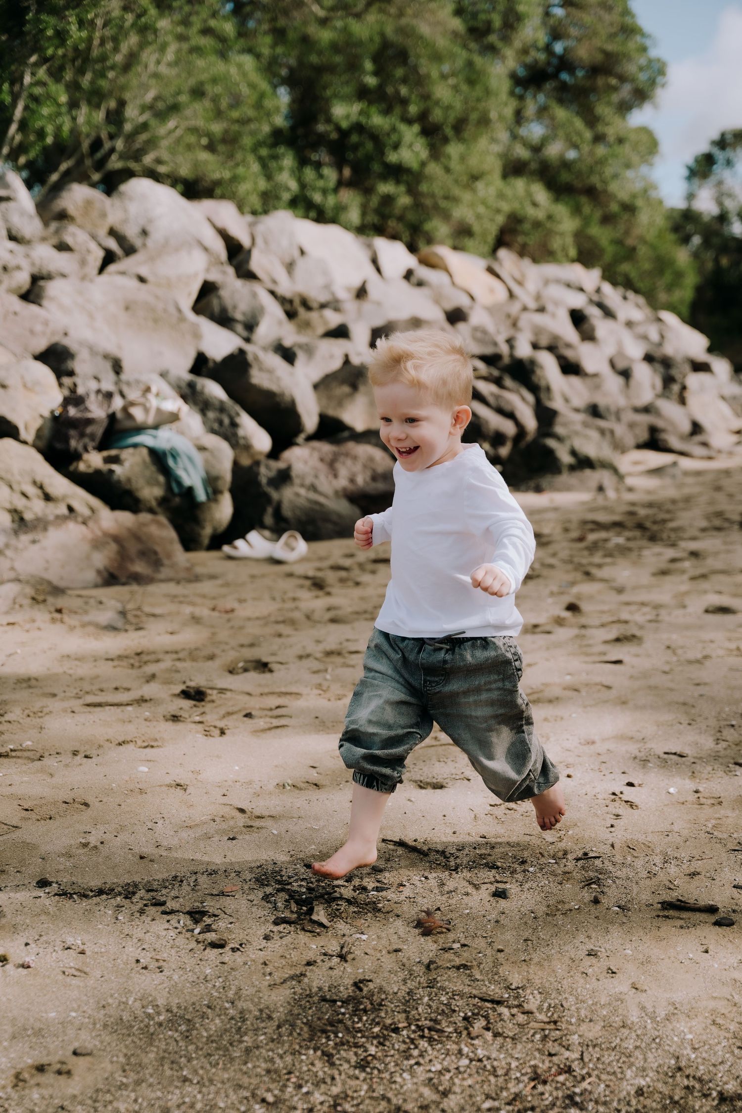 Playful movements captured in sequence on a sandy beach with rocky outcrops in the background.