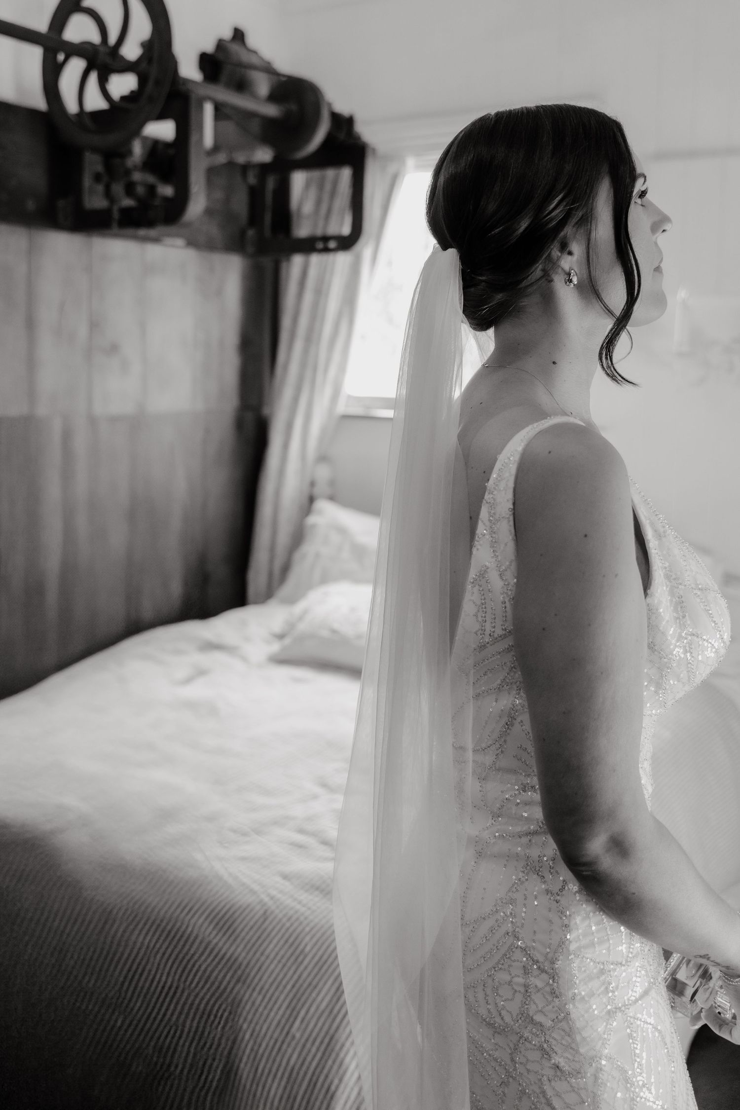 Black and white series showing details of a lace wedding dress in a sunlit bedroom.