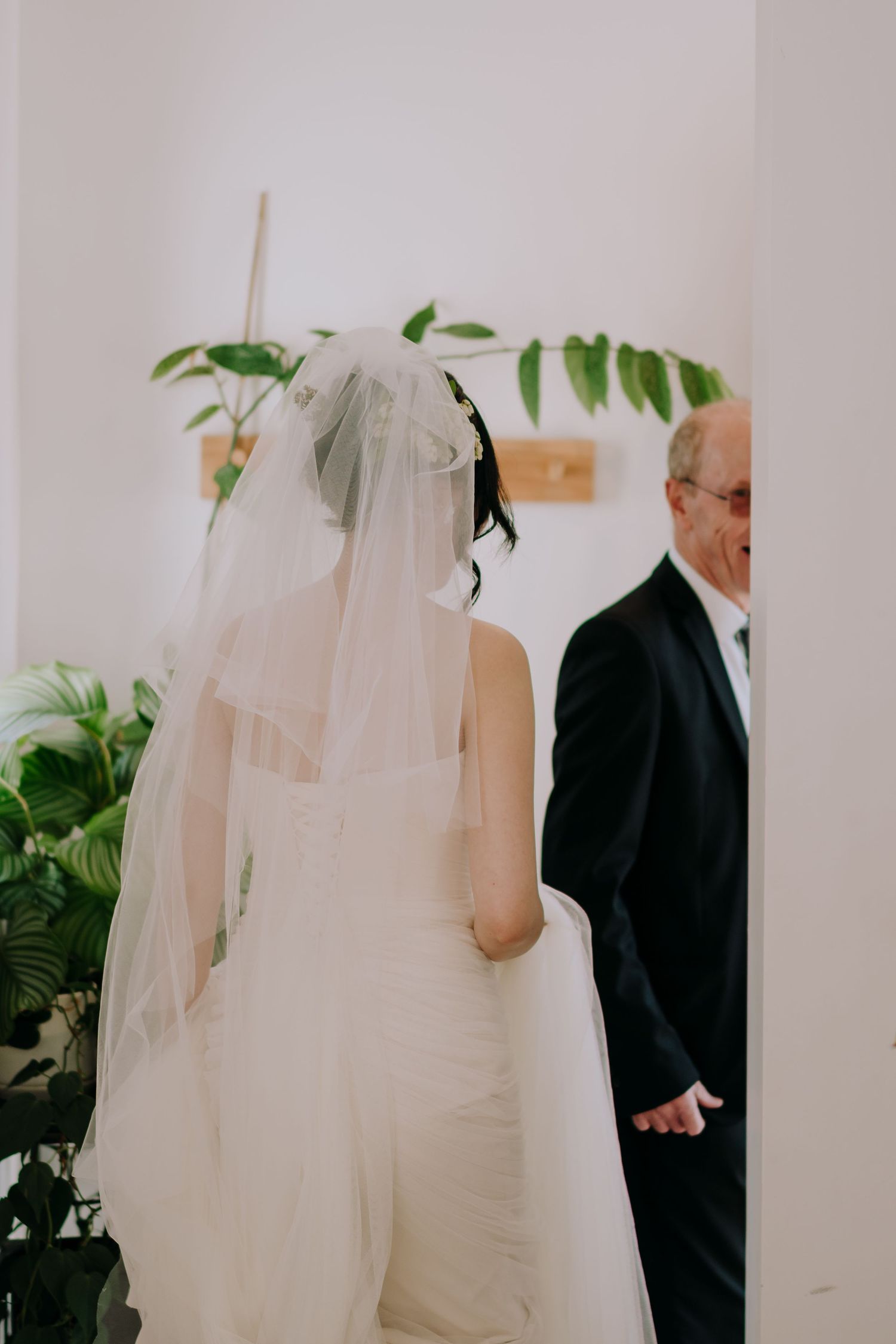 A wedding ceremony in progress with indoor plants and white decor visible in the background.