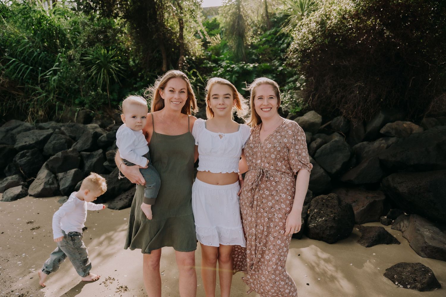 Group portrait session on a tropical beach with natural rock formations.