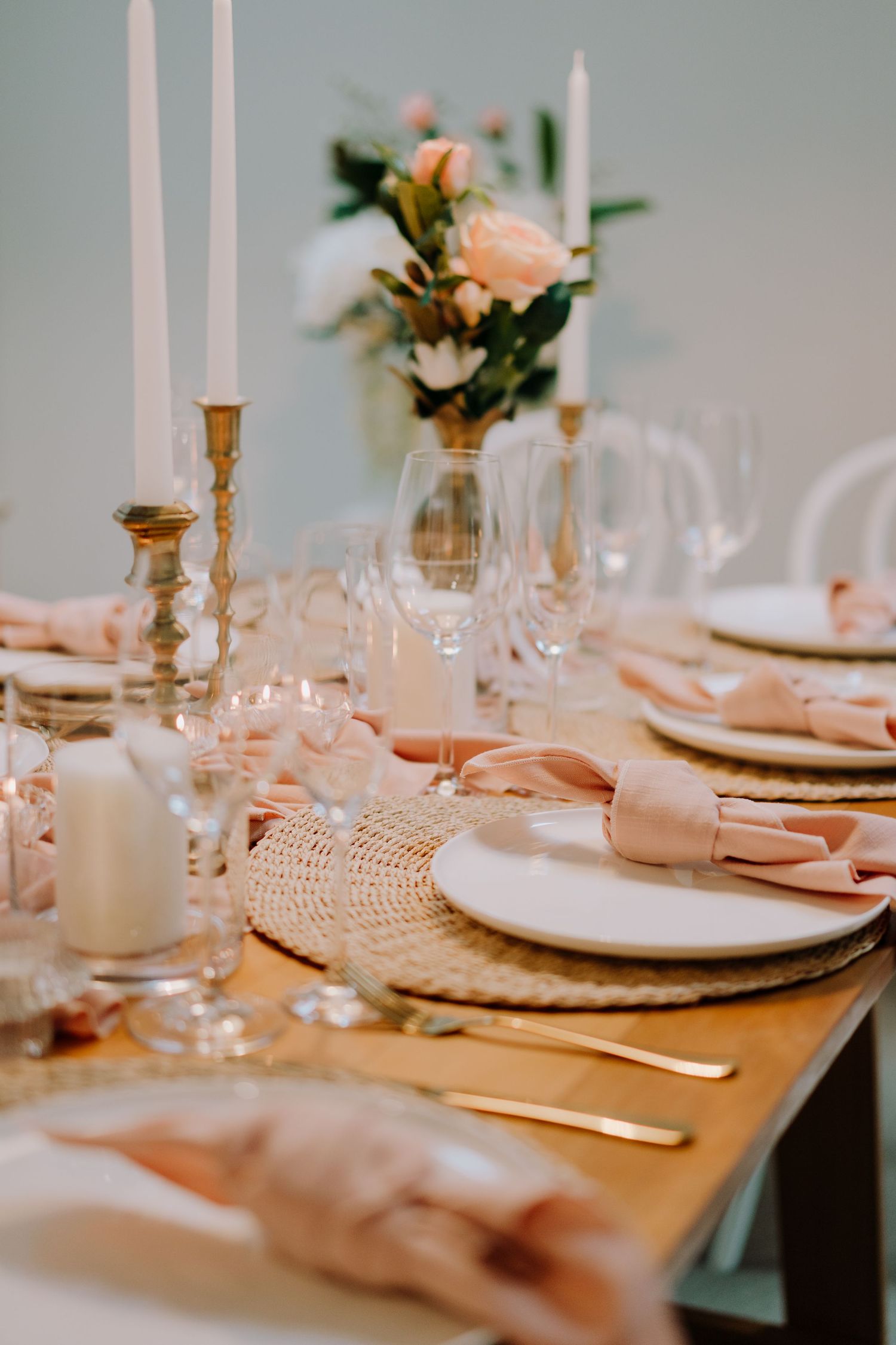 Elegant table settings with white candles, delicate glassware, and peach floral accents create a romantic dining atmosphere.