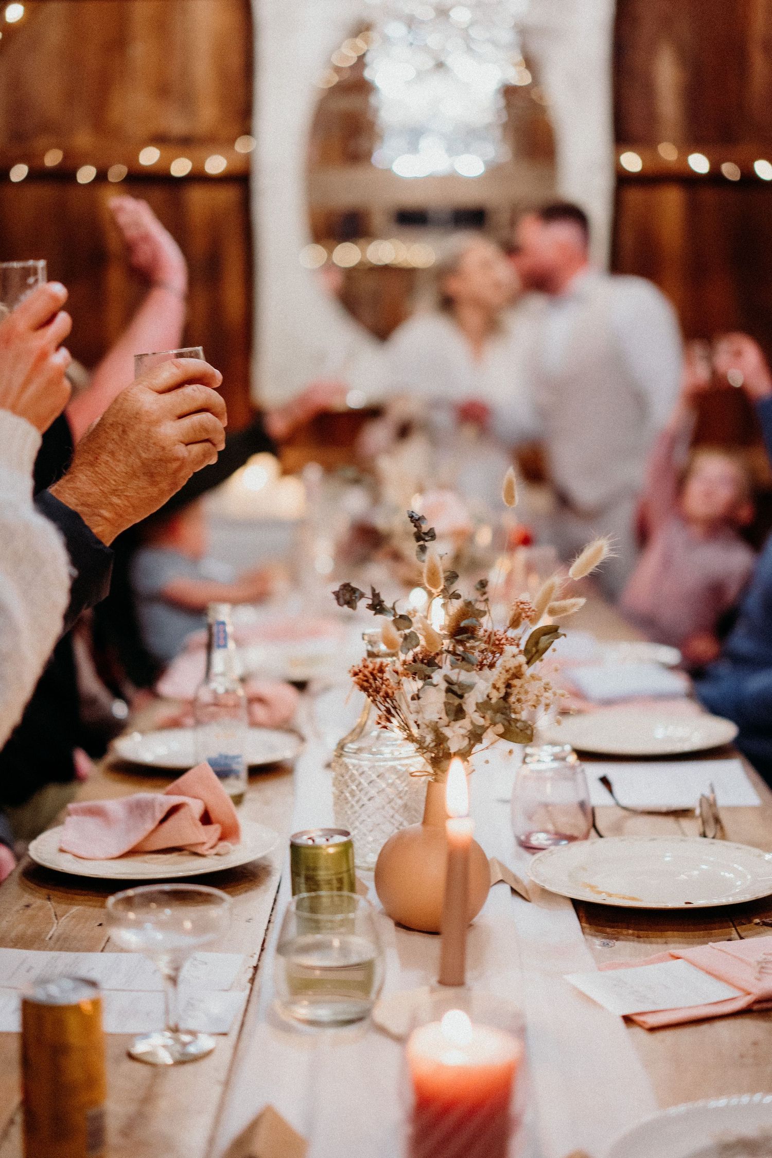 Elegant table setting with candles and dried flowers at rustic indoor celebration.