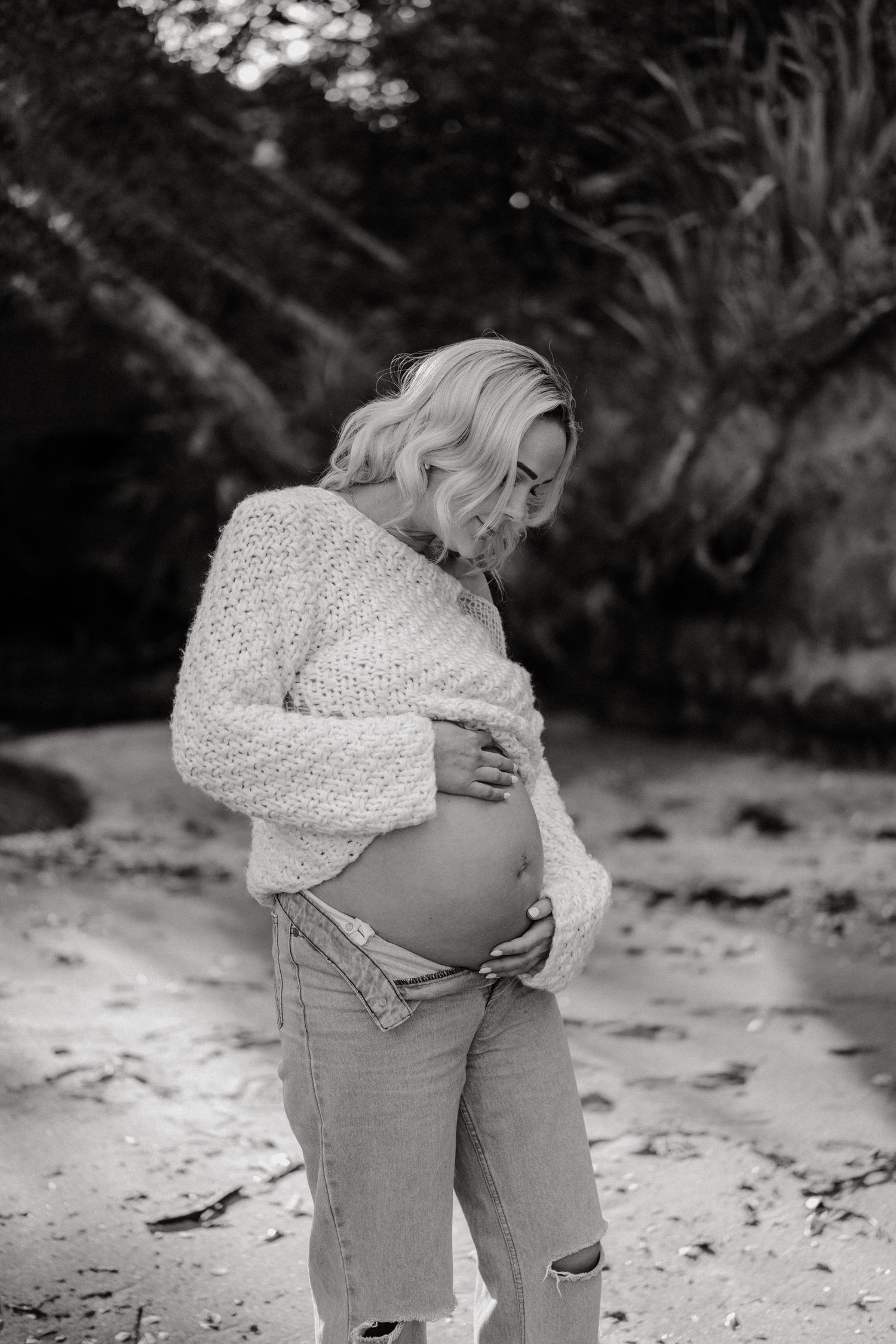 Maternity photo shoot in black and white showing pregnant belly in white knit sweater.