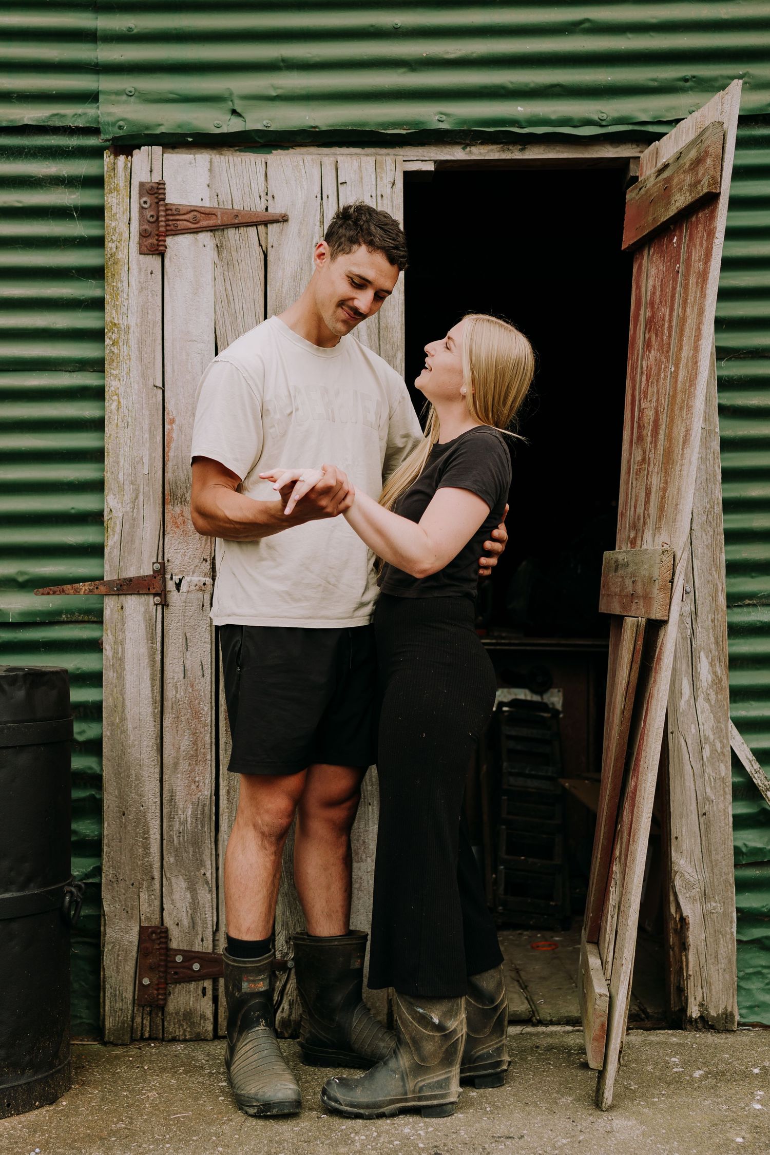 A couple sharing a tender moment in front of a rustic green barn door.