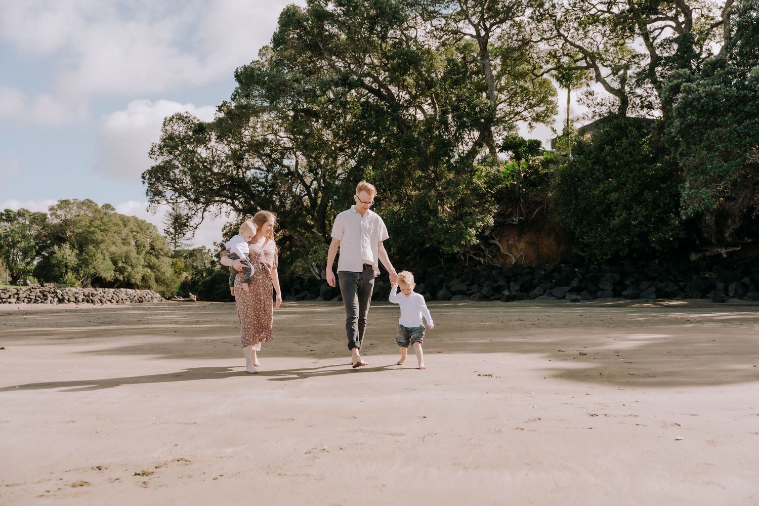 Couple walking together on a scenic beach path surrounded by lush tropical trees.