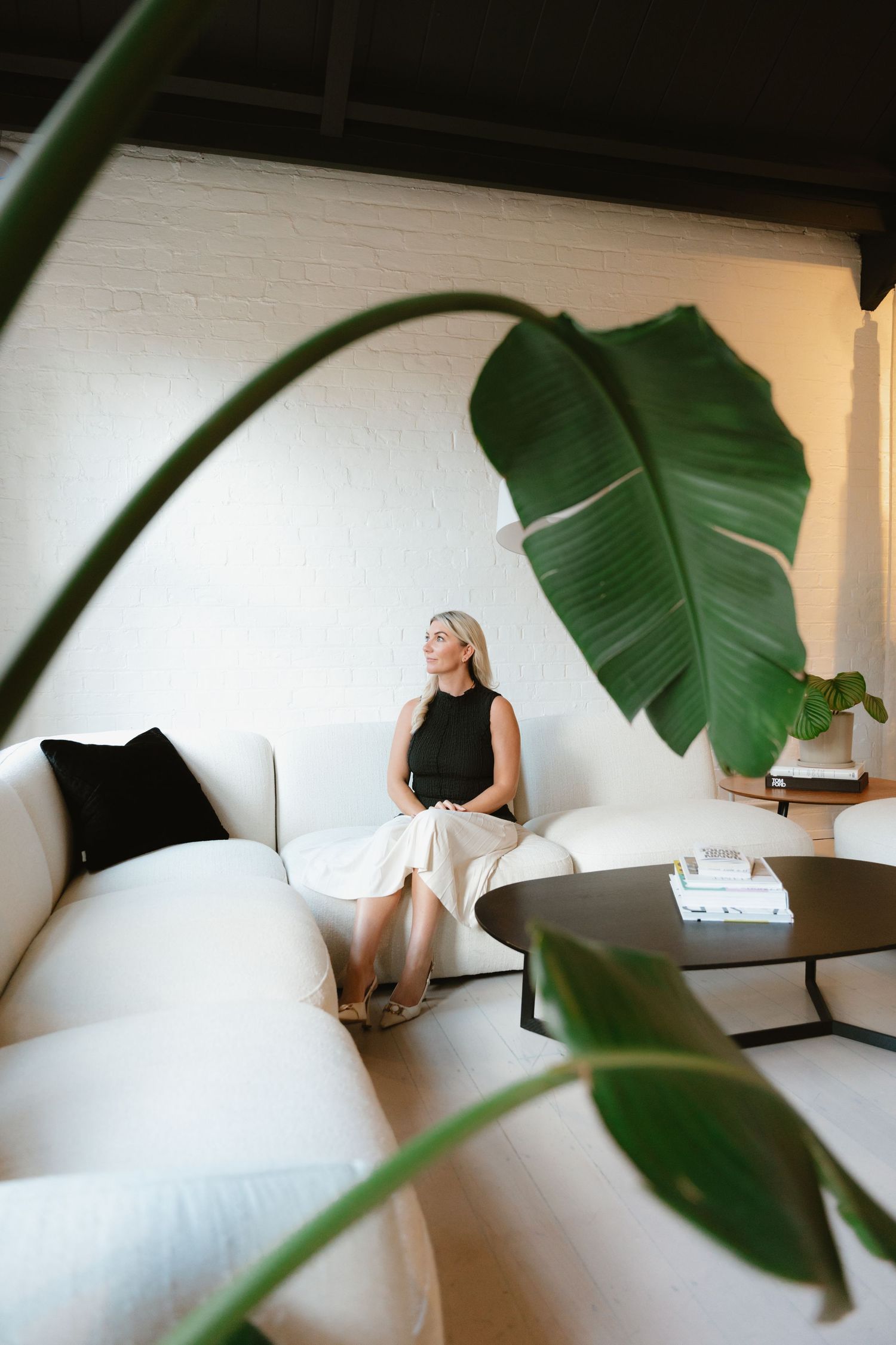 Minimalist interior scene with large tropical leaves and white walls creating a serene atmosphere.