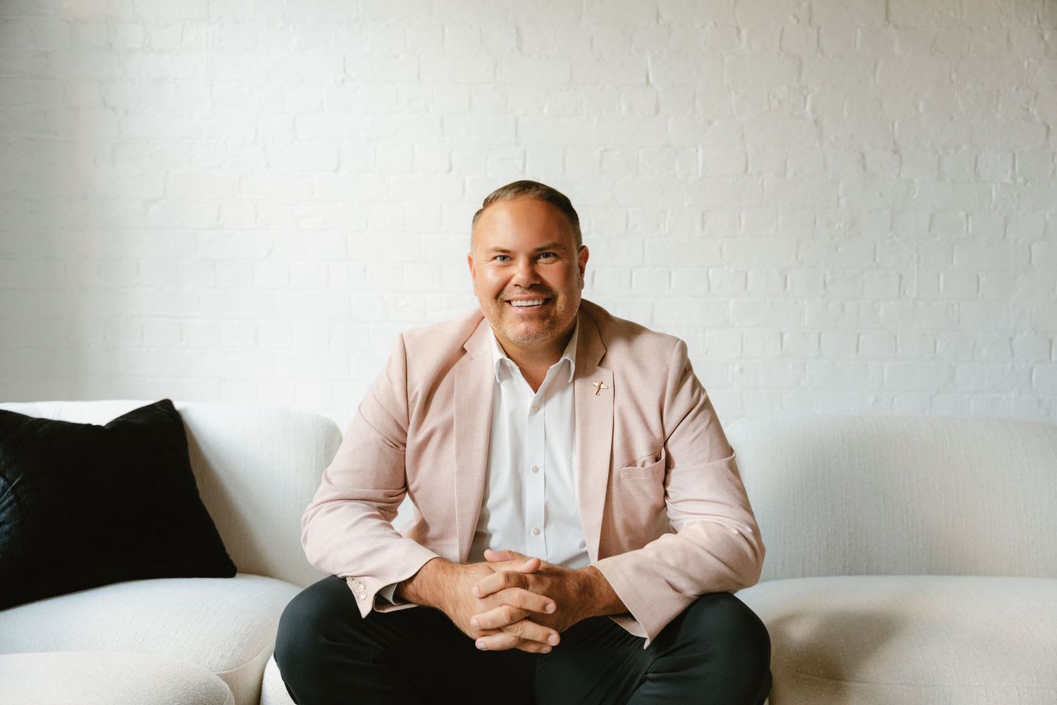 Professional headshot against white wall with person wearing light pink blazer.