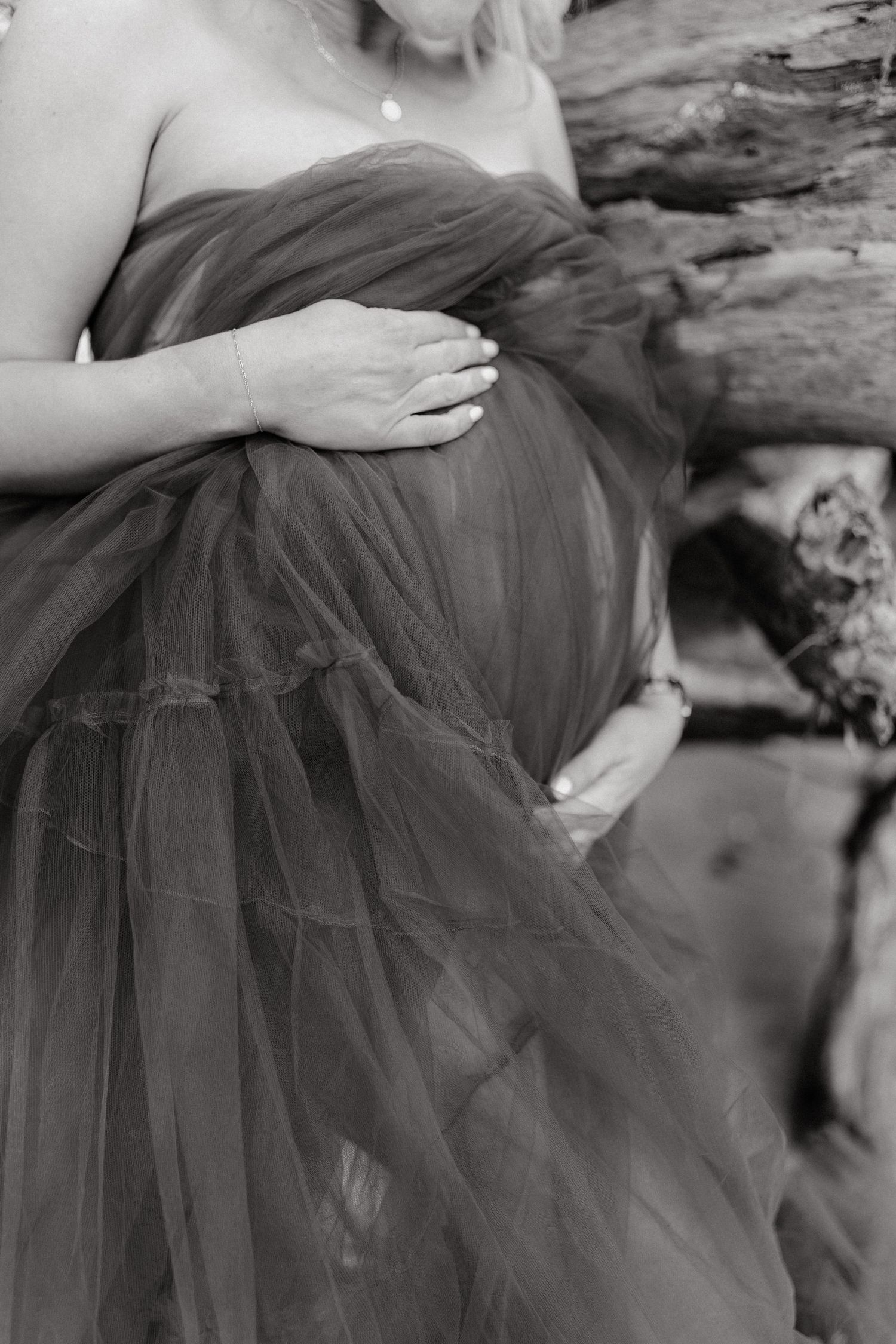 Artistic maternity photos featuring flowing black tulle skirt against natural backdrop.