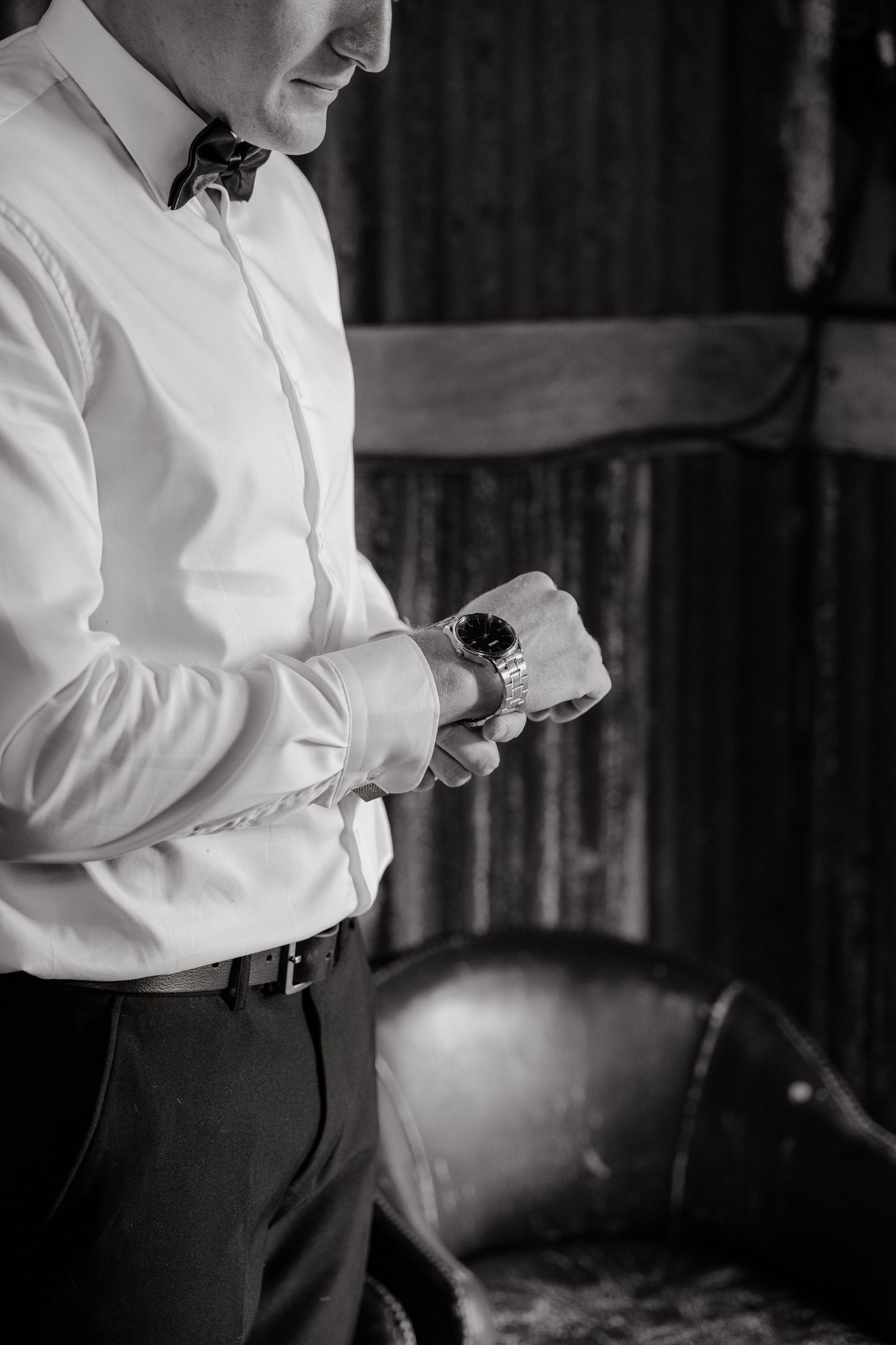 A series of black and white photos showing someone adjusting a watch or timepiece while wearing a white dress shirt.