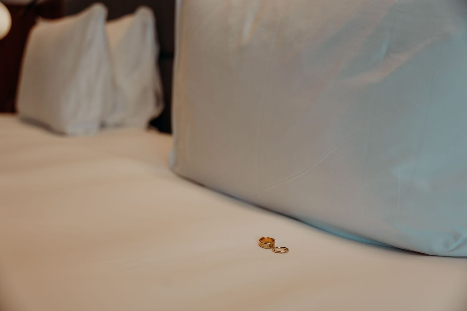A small golden key rests on white bedding, creating a minimalist composition against soft fabric textures.