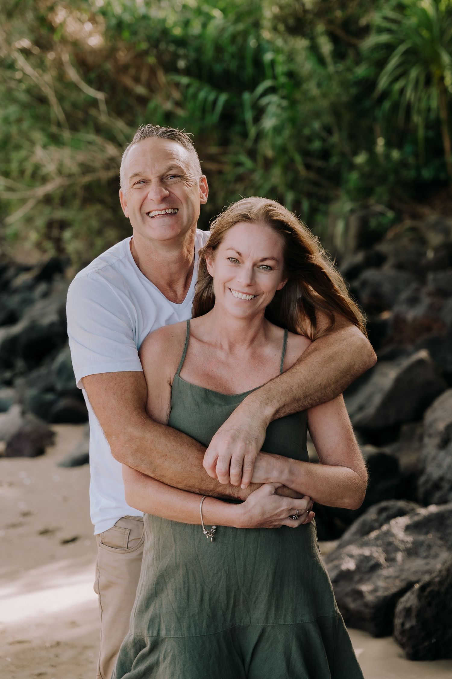 Casual beach portrait session with natural lighting and rocky coastal backdrop.
