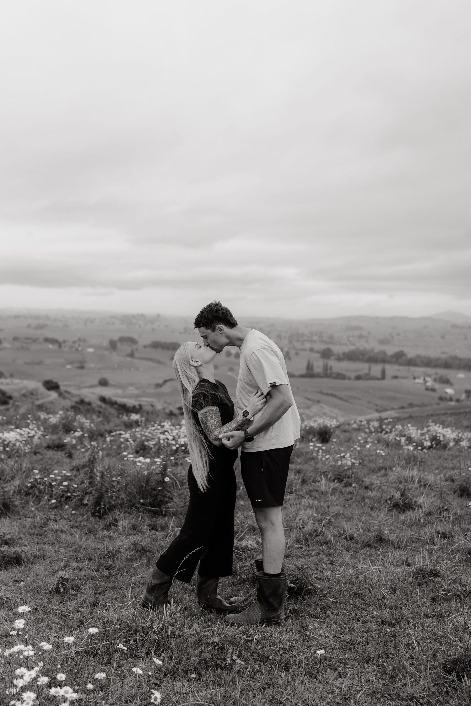 A couple sharing an intimate moment in a field of wildflowers on rolling hills.