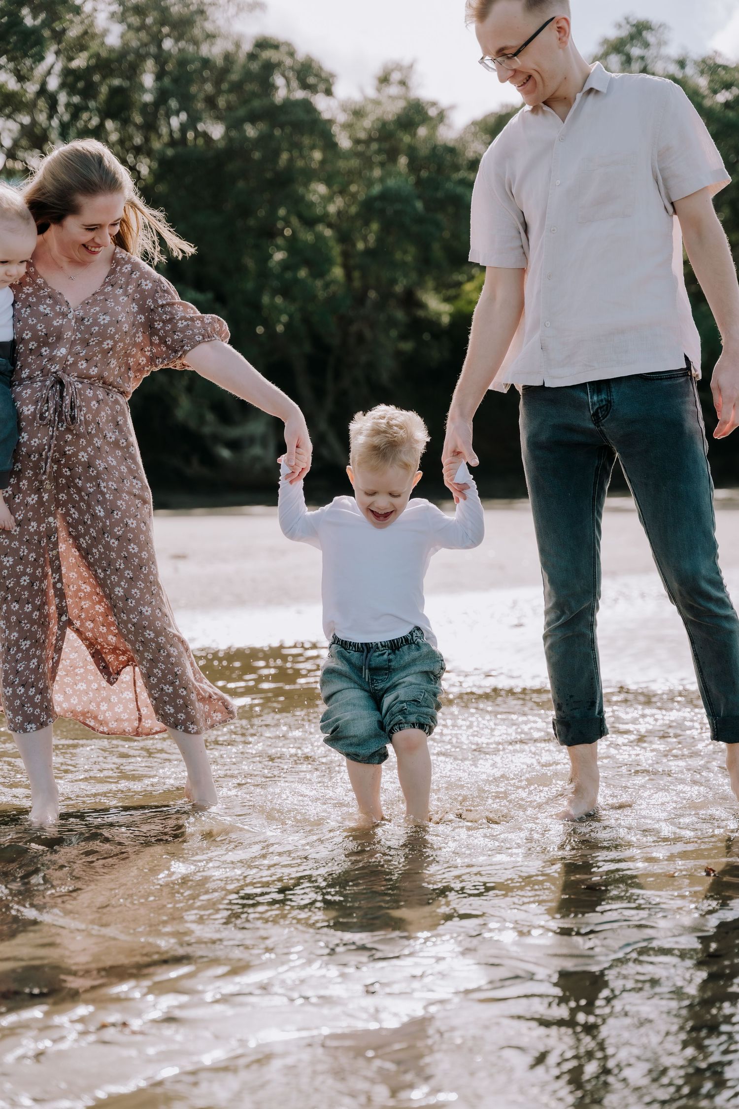 Family splashing and playing together in shallow ocean waves at the beach.