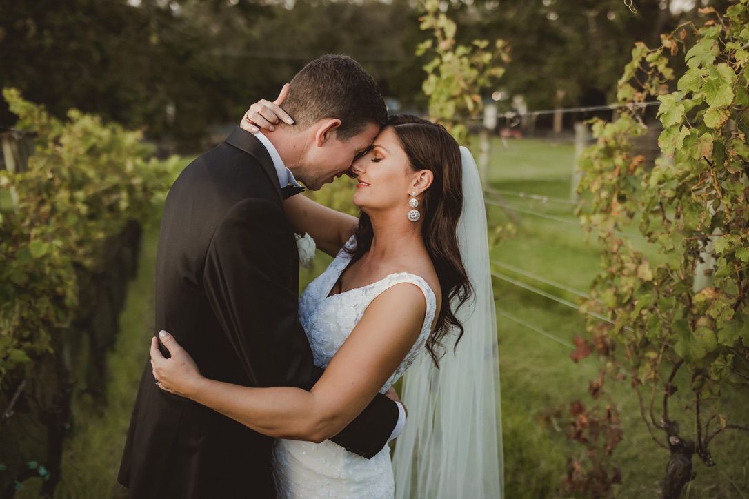 A romantic outdoor wedding scene with a couple embracing under lush greenery in a garden setting.