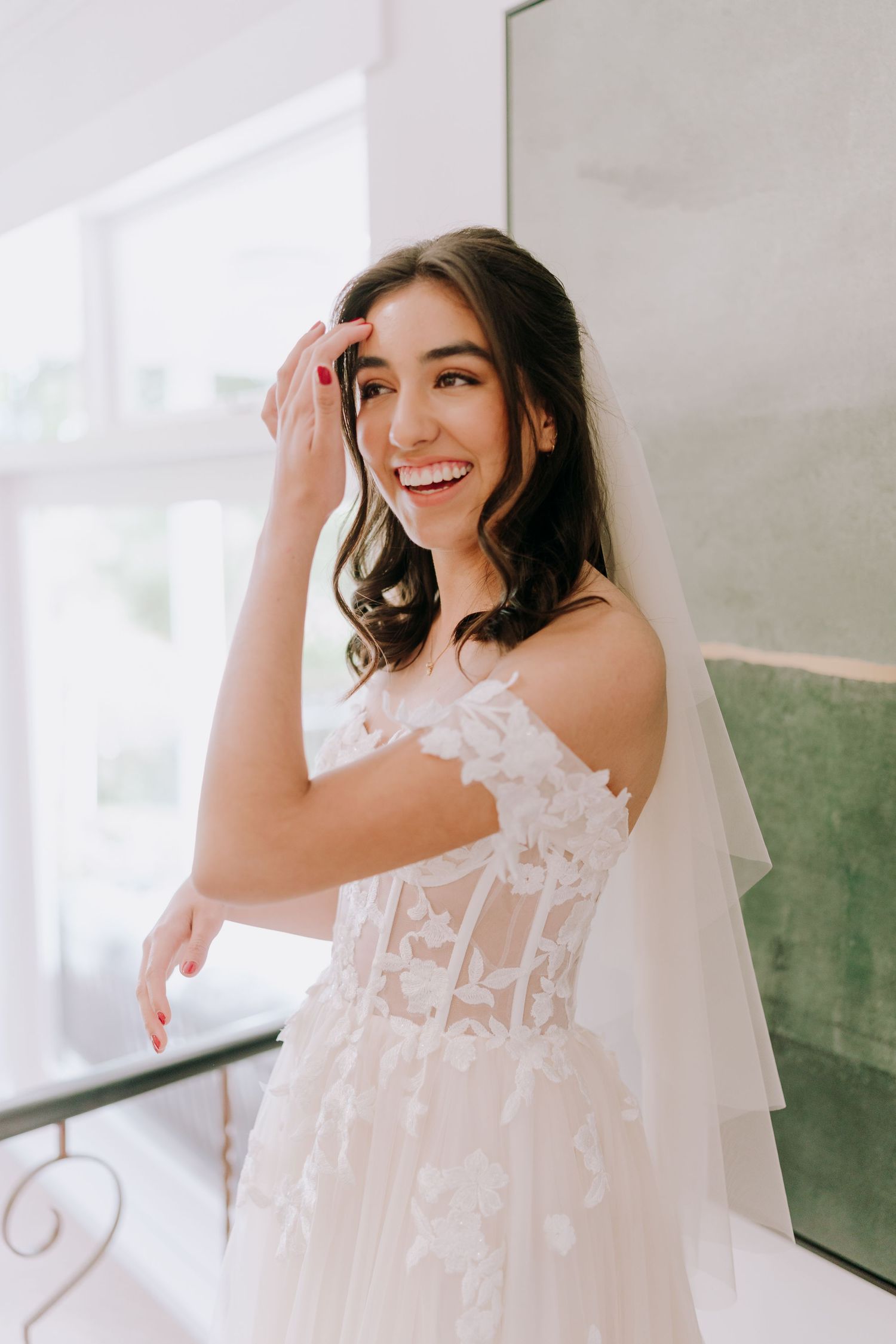 Joyful bride in lace wedding dress with flowing veil.