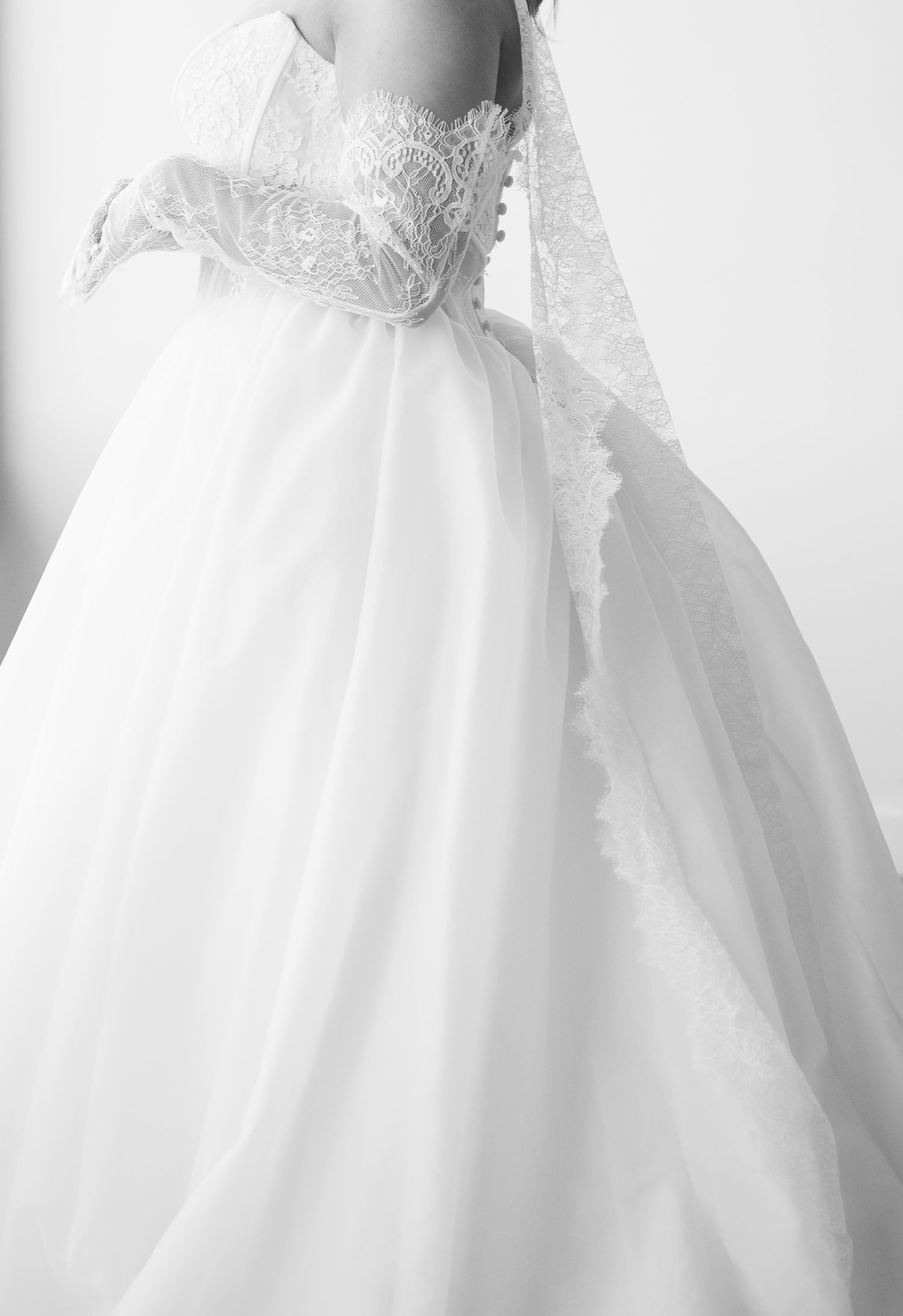 Elegant white ball gown wedding dress with lace bodice and flowing tulle skirt, paired with a lace veil.