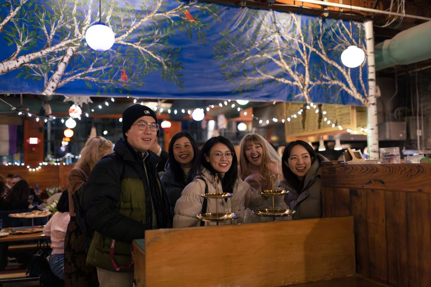 Winter scene of an outdoor market with snow-covered branches and twinkling lights creating a festive atmosphere.