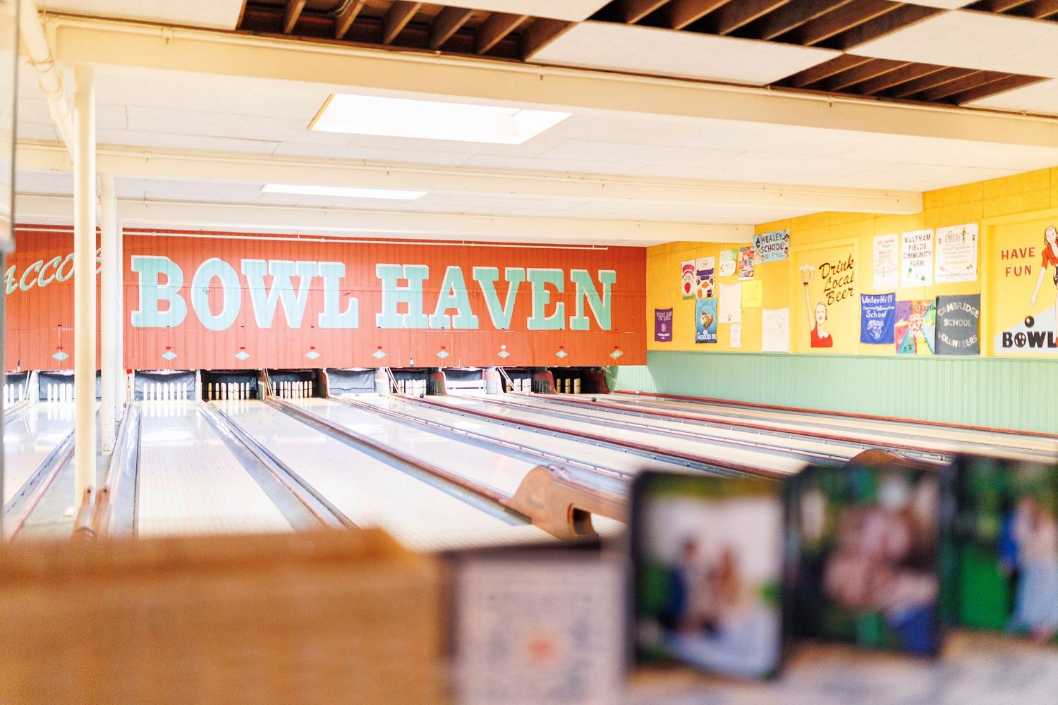 Convenience store interior with bright fluorescent lighting and colorful signage displays along the ceiling at Flatbreads in Somerville.