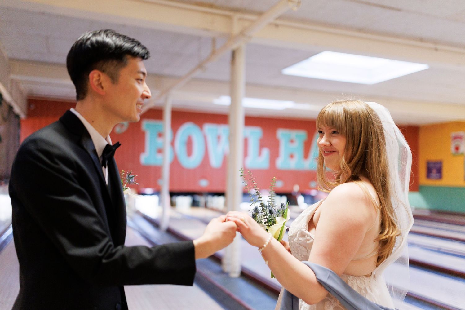 A couple sharing a playful moment at a bowling alley with lanes in the background at Flatbreads in Somerville.