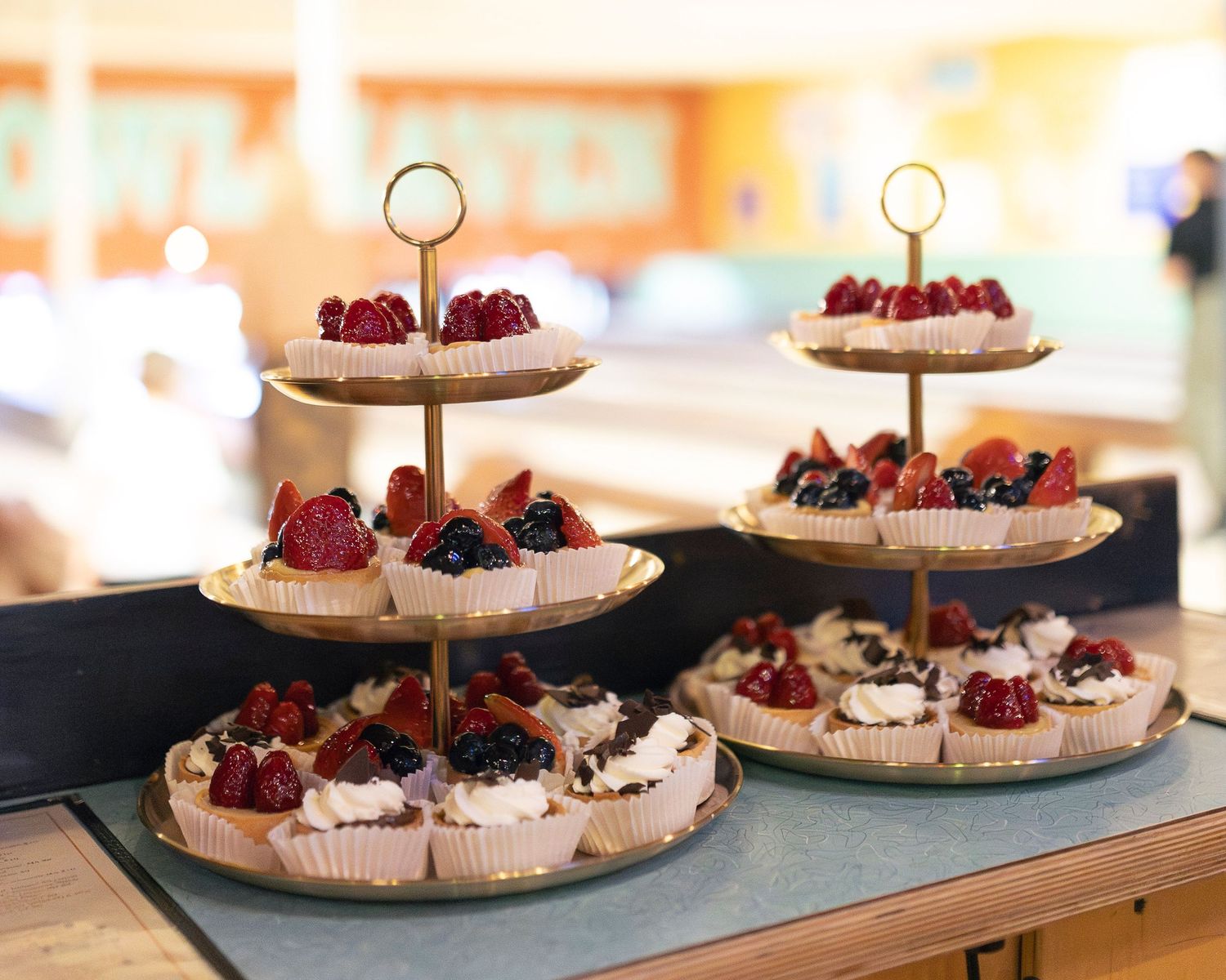 A multi-tiered dessert stand displays delicate pavlovas topped with fresh berries and cream on a marble countertop at Flatbreads.