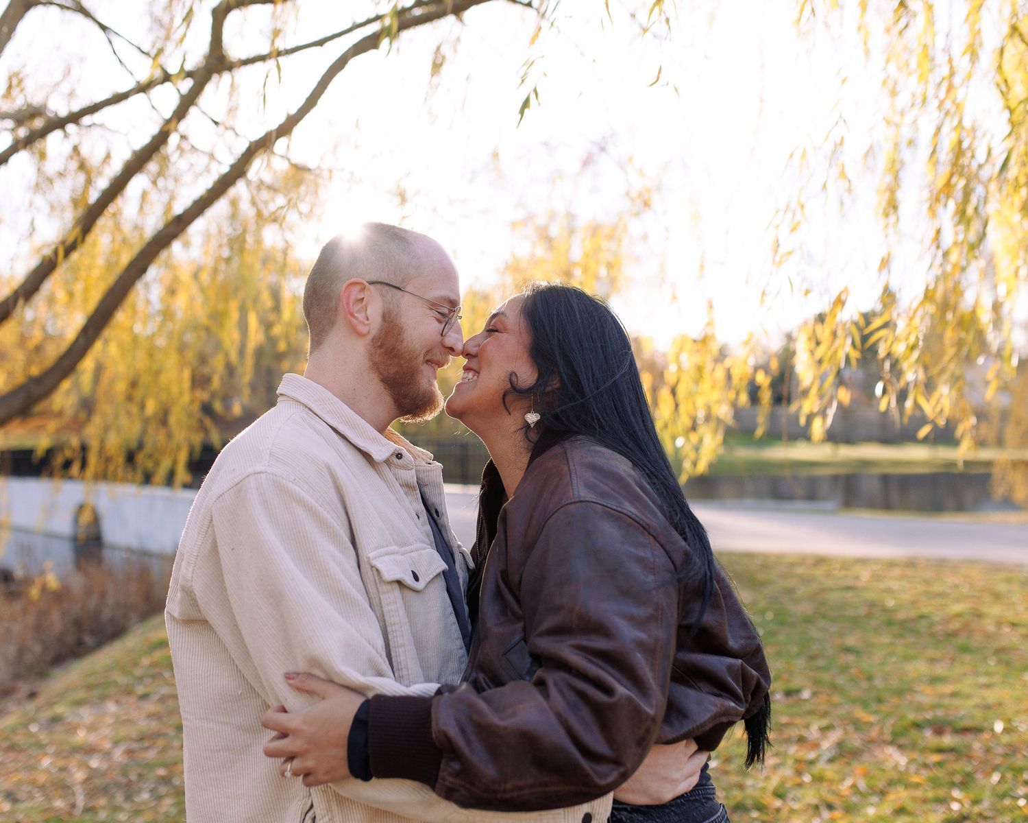 A romantic couple embraces under autumn trees during a golden sunset photo session.
