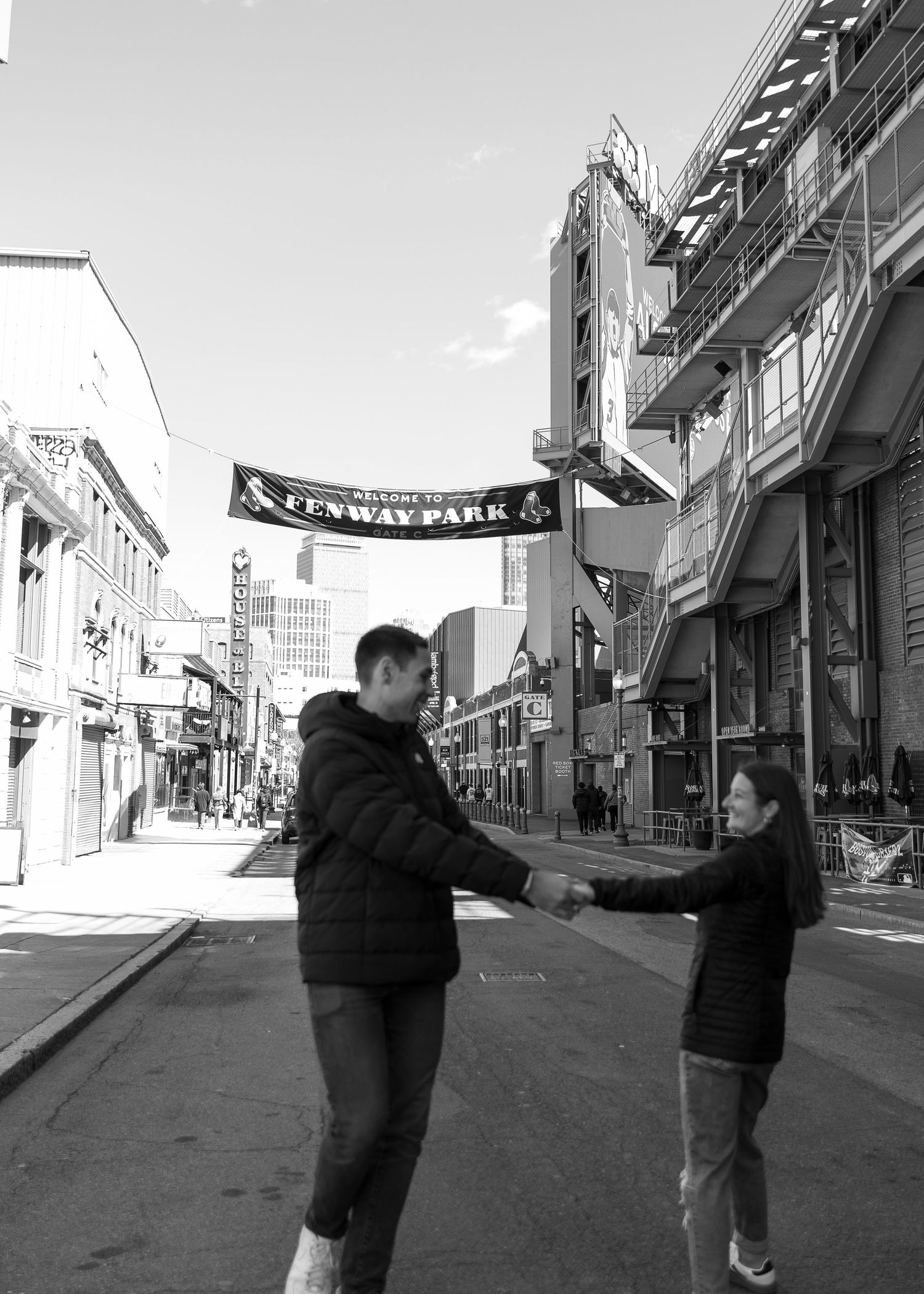 Black and white photo of couple holding hands outside Fenway Park stadium street in Boston, MA.