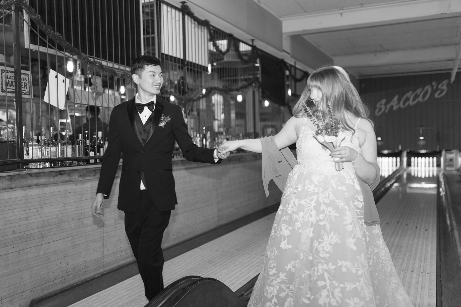 A couple in formal wedding attire walks together through a train station platform.