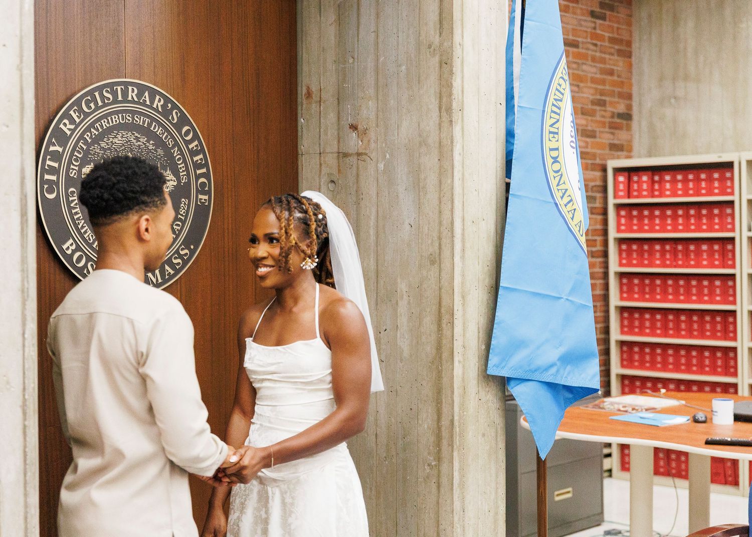 Couple in wedding attire holding hands at City Registrar's Office during civil ceremony.