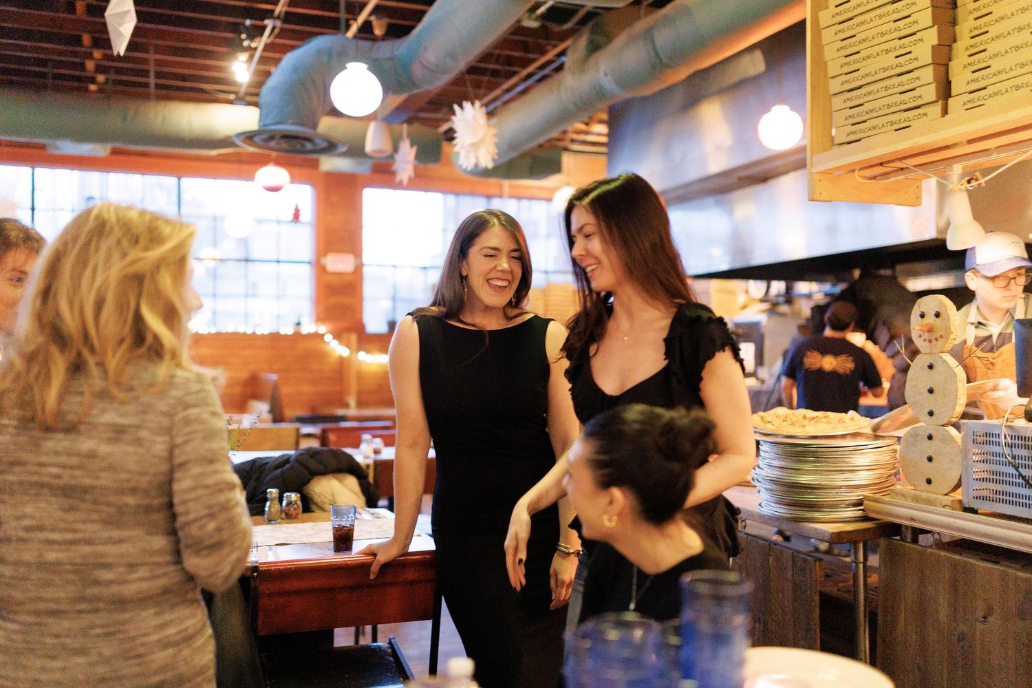 People dancing in a social setting with turquoise support columns and ambient lighting at Flatbreads in Somerville.