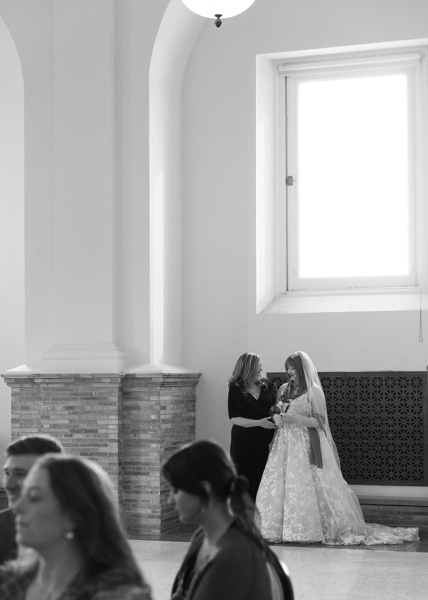 A black and white wedding photo showing a quiet moment in a church with guests seated in the foreground.